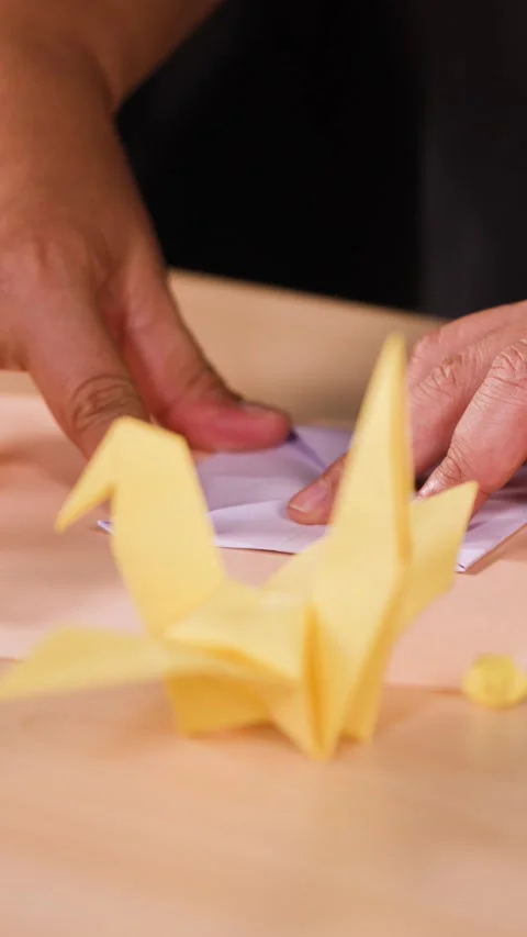 Close Up of Hands Folding Origami Paper Bird on Table Stock Footage 327116107