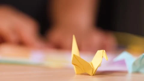 Close Up of Hands Folding Origami Paper Birds on a Table Stock Footage 327121010