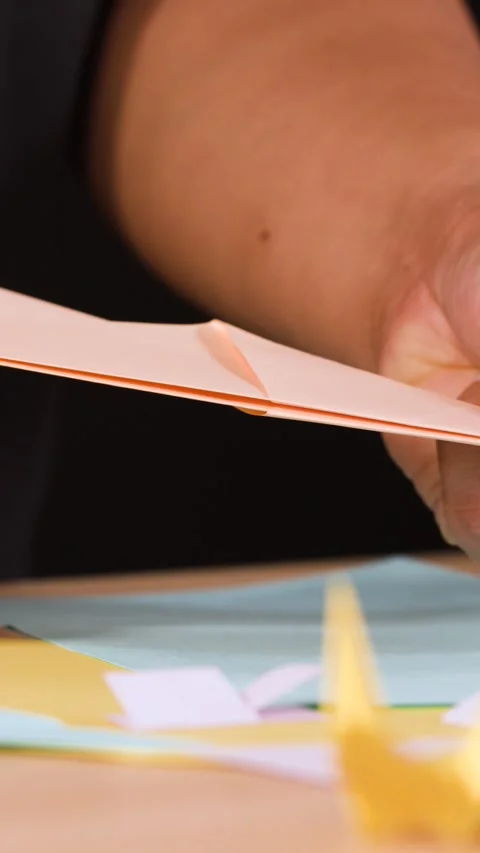 Close Up of Hands Folding an Origami Paper Airplane at a Table Stock Footage 327688594