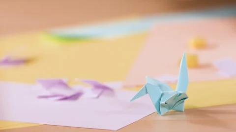 Close Up of Hands Folding Paper Origami Crane on Wooden Table Stock Footage 327258927