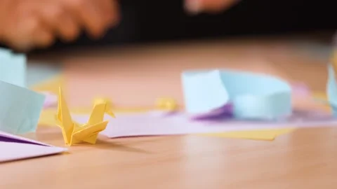 Close Up of Hands Folding Paper Origami on a Wooden Table Stock Footage 327260720