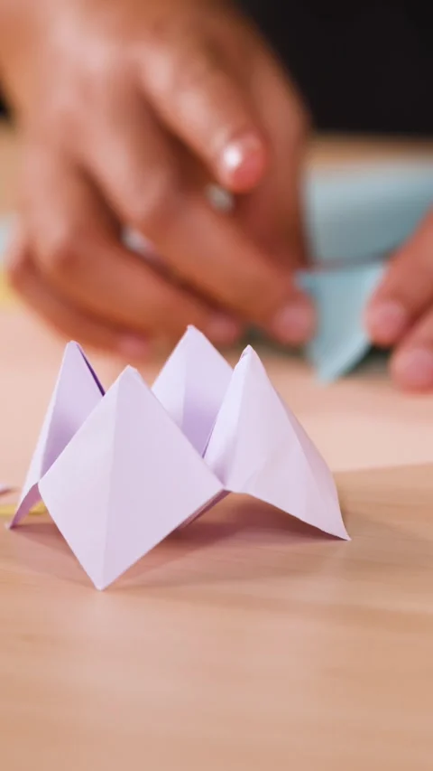 Close Up of Hands Folding Paper Origami on a Wooden Table Stock Footage 327446222