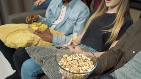 Close-up of the hands of friends taking popcorn while watching a movie Stock Footage 124038671