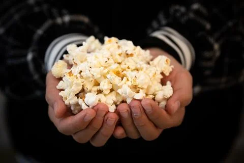 Close-up of hands full of popcorn. The hands of a teenage girl are holding po Stock Photos