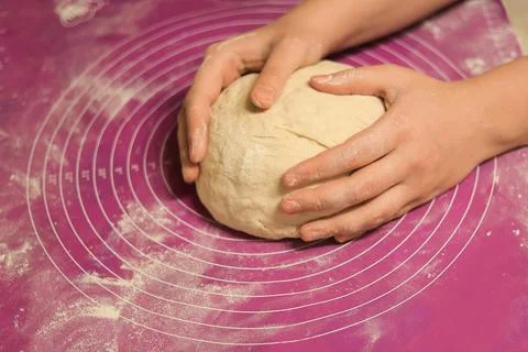 A close-up of hands gently shaping and rounding a large ball of fresh dough.. Stock Photos