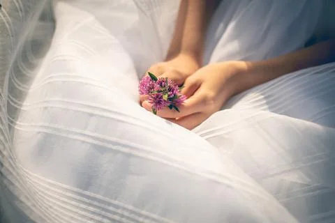 Close-up of the hands of a girl dressed as a communion holding some flowers Stock Photos