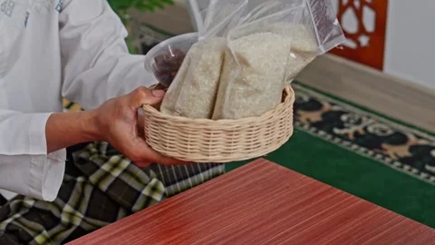 Close-up of hands giving basket of rice and dates for Zakat Al-Fitr Stock Footage 328987140
