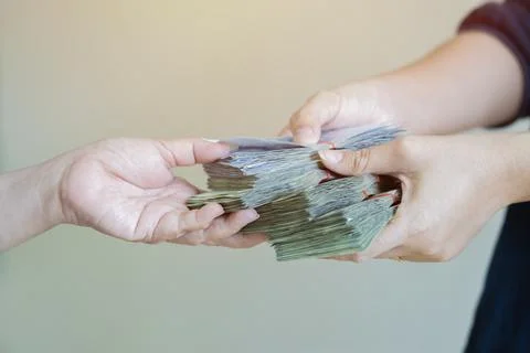 Close up hands giving stack of money over light gray background. Stock Photos