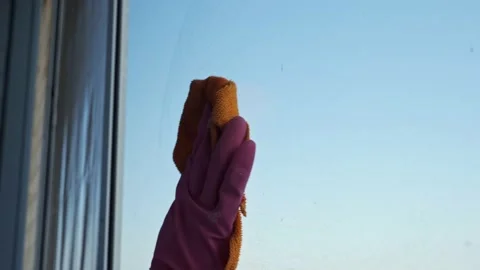 Close-up of hands in gloves cleaning the window with a rag against the Stock Footage 153036020
