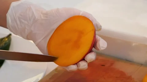 Close-Up of Hands in Gloves Slicing a Fresh, Ripe Mango Stock Footage 331781316