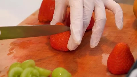 Close-up of hands in gloves slicing fresh strawberries on a wooden board. Stock Footage 331781786