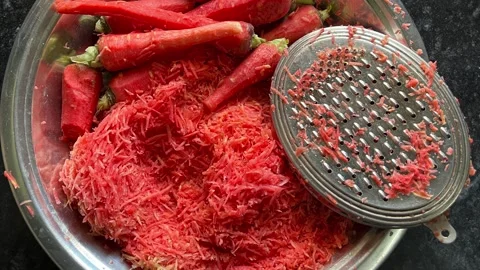 Close up of hands grating fresh red carrots in a stainless steel bowl Видео 328441258