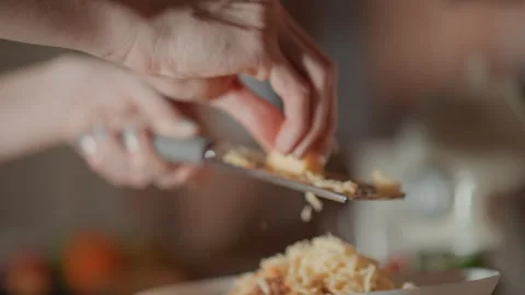 Close-up hands grating hard cheese over bowl with falling shavings and tactile Stock Footage 346643130