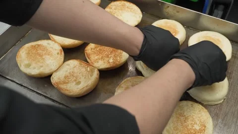 Close-Up of Hands on Griddle Making Fresh Sourdough English Muffins in a Commerc Stock Footage 331633801