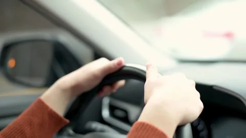 Close-up of hands gripping a steering wheel while driving. The driver maintai Stockbeeldmateriaal 276397903