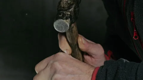 Close-up of hands with a hammer isolated on a dark background. Media. The hammer 動画素材 229967318