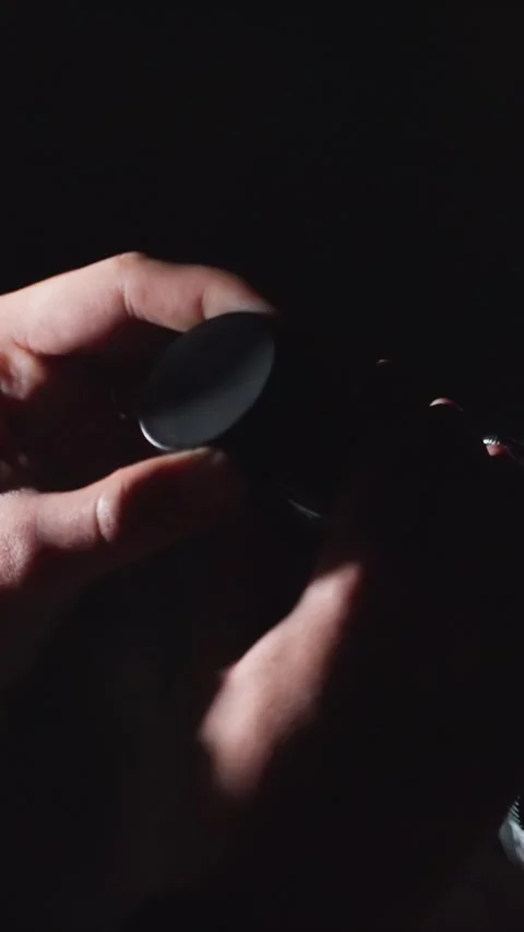 Close up of hands handling black camera lens cap and optical device in dim Stock Footage 345545283