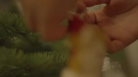 Close-up of hands hanging doll Christmas decoration on pine tree 스톡 동영상 334031710