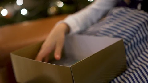 Close-up of the hands of a happy child pulling out of a gold gift box colored ma Stock Footage 120682210
