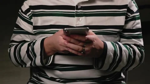 Close-up of hands holding and typing on a smartphone with a striped shirt Stock Footage 339188415