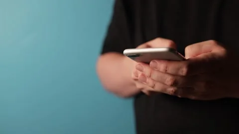 Close-up of hands holding and typing on a modern smartphone with a blue Stock Footage 340268565