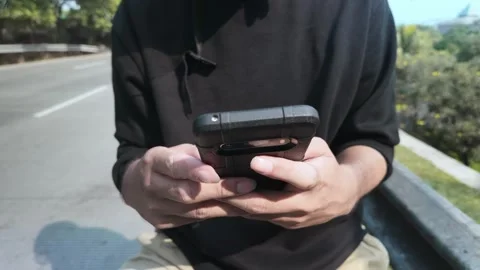 Close Up Of Hands Holding And Using Smartphone On The Roadside Video stock 339184957