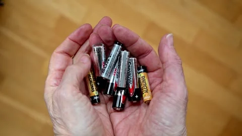 Close-Up Of Hands Holding A Battery Pack And Loose Batteries In A Pile Stock Footage 325418341