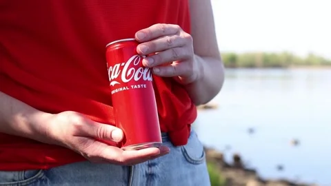 Close-up of hands holding a can of Coca-Cola Original Taste on a nature back Stock Footage 334792424
