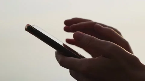 Close-up of hands holding cell phone and scrolling social media content outdoor. Видео 253967375