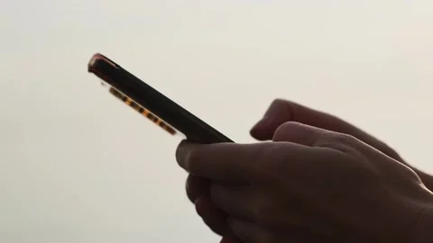 Close-up of hands holding cell phone and scrolling social media content outdoor. Stockbeeldmateriaal 255002480