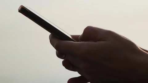 Close-up of hands holding cell phone and scrolling social media content outdoor. Видео 257289243