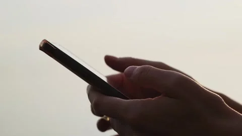 Close-up of hands holding cell phone and scrolling social media content outdoor. Vidéo 262019902