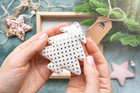 Close-up hands holding Christmas tree toy made of white fabric with gold dotted Stock Illustration