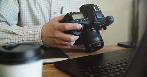 Close-Up of Hands Holding DSLR Camera at Wooden Desk Stock Footage 308377760