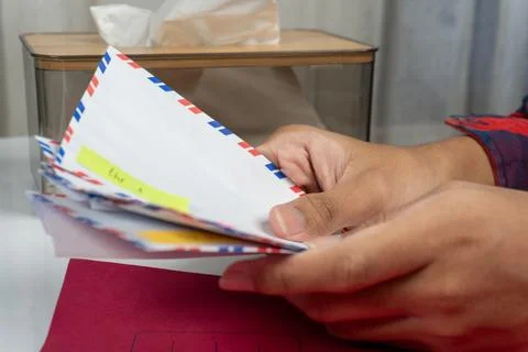 Close up of hands holding envelopes on table with red document folder Stock Photos