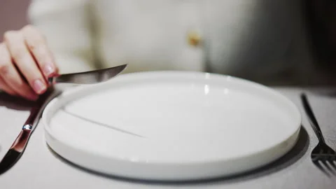 Close up of hands holding fork and knife over an empty white plate in a Stock Footage 332568376