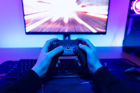 Close up of hands holding game controller while playing fast racing video g.. Stock Photos