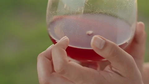 Close up of hands holding glass with red liquid and visible condensation with Stock Footage 345849203