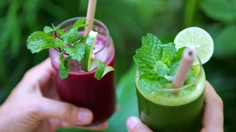 Close-up hands holding glasses with refreshing smoothies. Bright smoothies Stock Footage 278408572