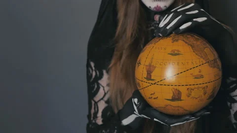 Close-up of hands holding a globe. hands of a woman in the image of death santa Stock Footage 150462842