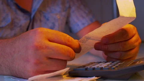 Close-up of hands holding a large paper receipt under a desk lamp Stock Footage 336983229