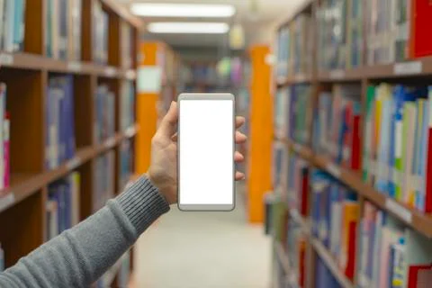 Close up Hands holding mobile smart phone with background of books on shelf a Foto stock