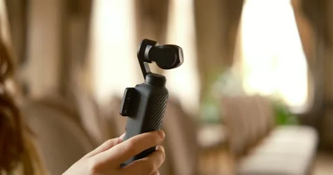 Close up of hands holding modern DJI Osmo Pocket 4 camera filming interior Stock Footage 335988518