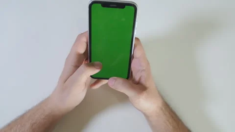 Close-up of hands holding a modern smartphone with a green screen, perfect for Stock Footage 296848720