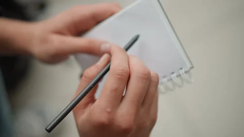 Close up of hands holding notebook and pen ready to write with soft lighting Stock Footage 346652553