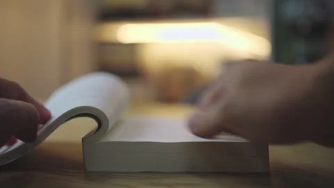 Close-up of Hands Holding Open Book on Wooden Table to Read and Study. Stock Footage 338184108