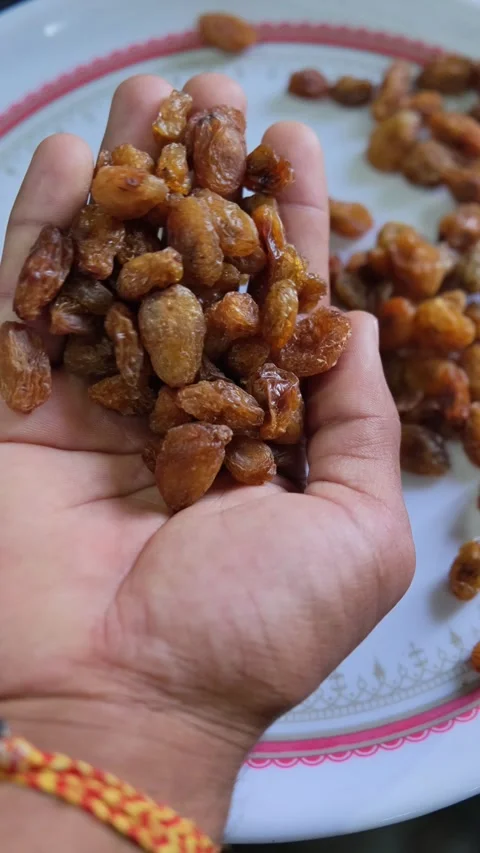 Close up of hands holding a pile of sweet brown raisins over a plate 库存影片 333202991