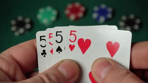 Close-up of hands holding playing cards showing four fives or quads, with poker Stock Footage 332866828
