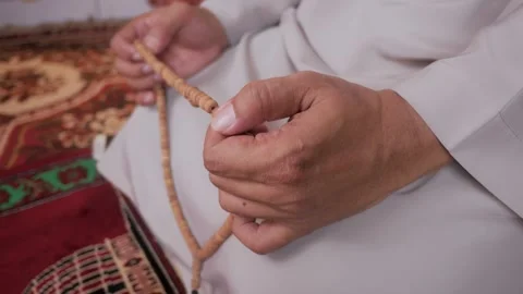 Close up of hands holding prayer beads in a mosque Stock Footage 323164189