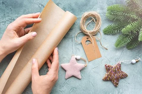 Close-up of hands holding a roll of wrapping craft paper. DIY Christmas gift. Stock Illustration